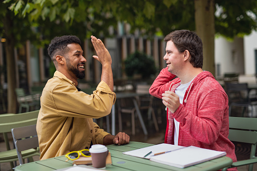 Two friends sharing a high-five at an outdoor cafe