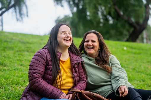 Mother and daughter laughing together outdoors in a park